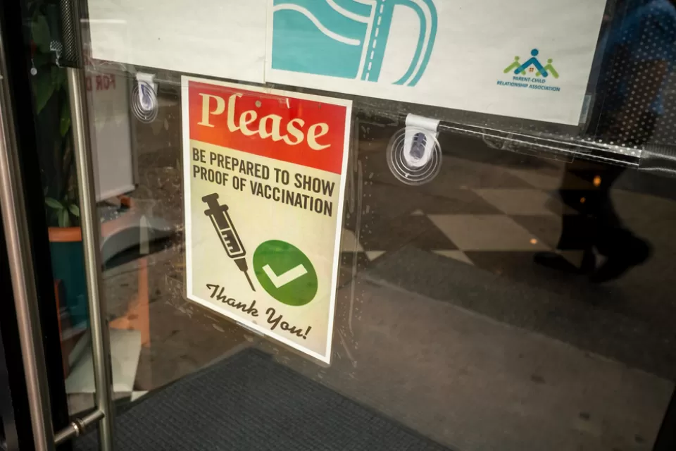 A sign on a door says proof of vaccine is required to enter.